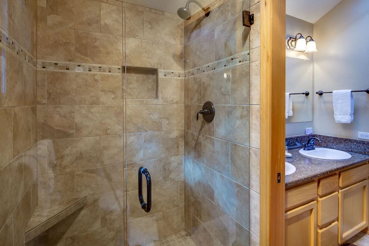 Modern bathroom with dual sinks, a glass walk-in shower, and stylish tile work. The space is calming and functional, offering everything needed for morning or evening routines.