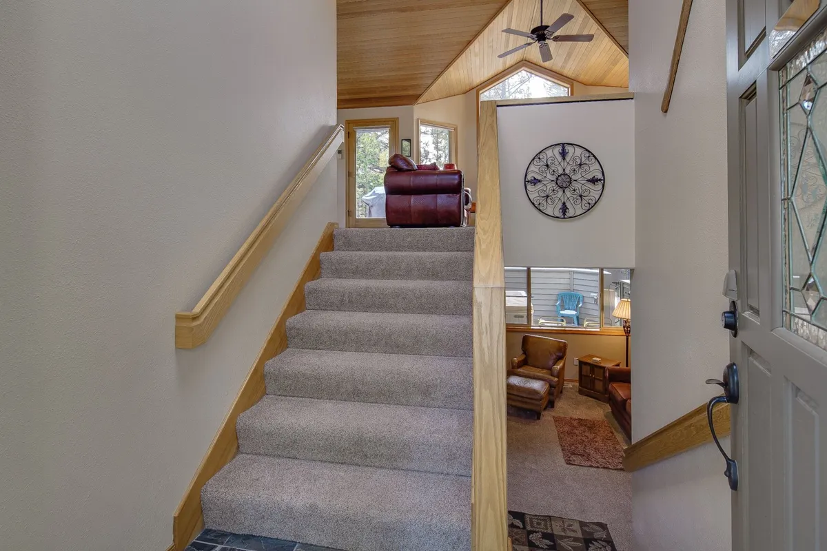 The photo features a staircase, large windows with views to the outside, and cozy recliner chairs. Soft daylight fills the space, blending interior comfort with hints of the natural world beyond.